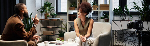Two young professionals converse during a interview in a stylish, plant filled studio.