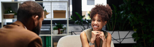 Young woman smiles and engages in discussion with a man during a interview in an studio.
