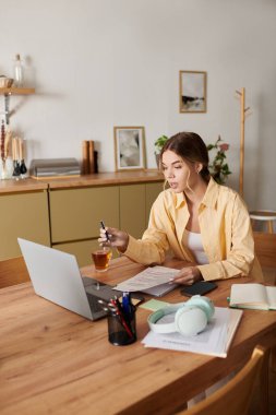 Evdeki derslerine odaklanan genç ve güzel bir kadın. Etrafında sıcak ve davetkar bir ortam var..