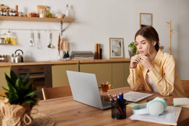 Genç bir kadın özenle ev masasında çalışıyor, çayını yudumluyor ve işine dalmış..