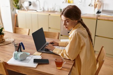 Yetenekli bir kadın ahşap masadaki işine odaklanmış, evinde sıcak bir fincan çayın keyfini çıkarıyor..