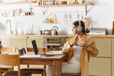 Parlak ve rahat mutfak ortamında müzik dinleyen genç bir kadın çalışıyor..