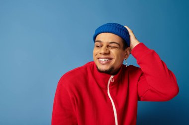 Genç adam kendine güveni ve kişiliği canlı bir mavi arka plana karşı ifade ediyor..