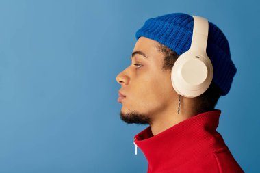 Modayı takip eden genç bir adam mavi bir bere ve kulaklık takıyor, cesur tarzını sergiliyor..