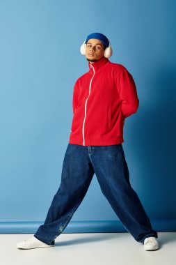 Şık bir genç adam parlak mavi bir arka plana karşı canlı bakışlarını sergiliyor..