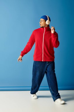 Şık bir siyah adam bereli ve kırmızı ceketli mavi bir fona karşı güven yayıyor..