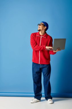 Tarz sahibi genç siyah bir adam dizüstü bilgisayarla gülümsüyor, enerjik bir enerji yayıyor..