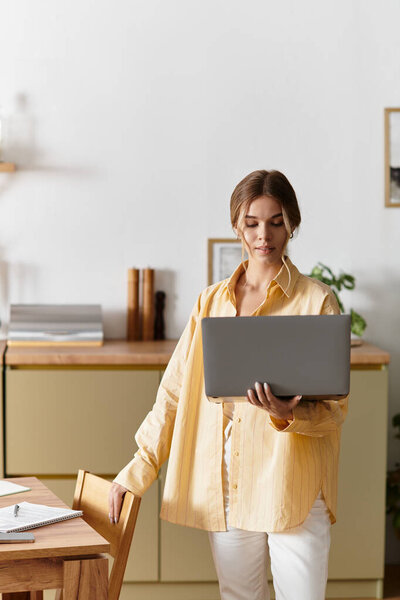 Bright and cozy home setting features a young woman engaged in work on her laptop.