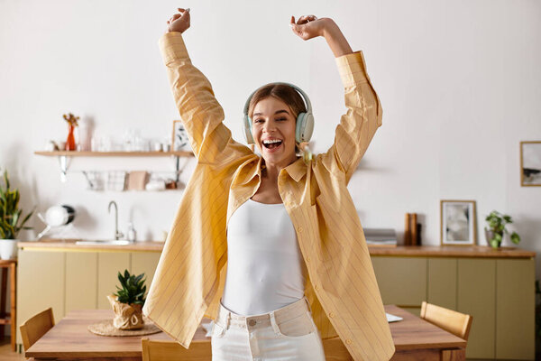 Возбужденная девушка танцует дома в наушниках, наслаждаясь любимыми мелодиями.