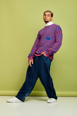 Genç adam rengarenk çizgili bir sweatshirt 'ün içinde kendine güvenerek poz veriyor..