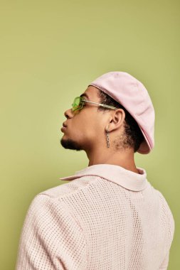 Pembe polo ve düz şapkalı genç adam canlı bir ortamda kendine güven ve tarz yayar..