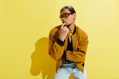 Genç bir Afrikalı Amerikalı, bir stüdyoda moda bir bombacı ceketiyle tarzını sergiliyor..