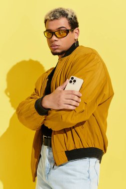 Genç Afrikalı Amerikalı bir adam, modaya uygun bir bombacı ceketi giyen bir stüdyoda güven içinde poz veriyor..