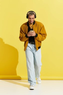 Genç bir Afrikalı Amerikalı, parlak bir stüdyoda kulaklıklarıyla müzik dinleyerek güvenle yürüyor..