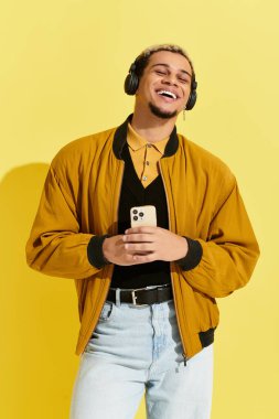 Modayı takip eden genç bir adam kendine güvenerek parlak bir stüdyoda büyük bir gülümsemeyle müzik dinliyor..