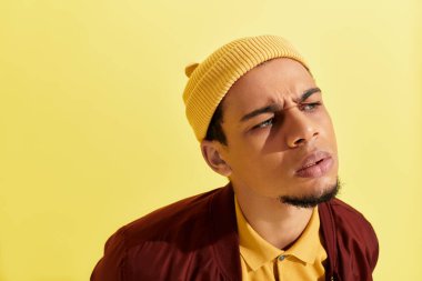 Genç Afrikalı Amerikalı adam, sarı arka planlı canlı bir stüdyoda moda sergiliyor..