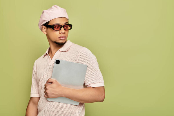 A confident young Black man in a pink polo, flat cap, and sunglasses.