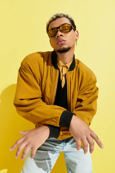 A confident young African American man showcases his trendy bomber jacket in a bright studio.