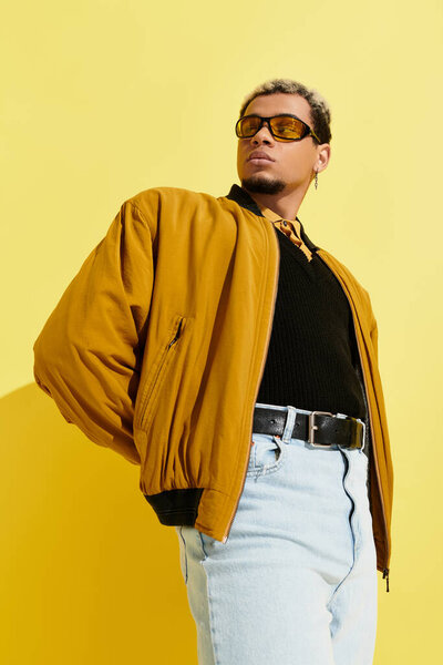 A young african american man showcases his trendy bomber jacket with confidence in a studio setting.
