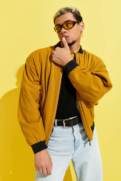 A stylish young Black man poses confidently in a chic bomber jacket, showcasing modern flair.