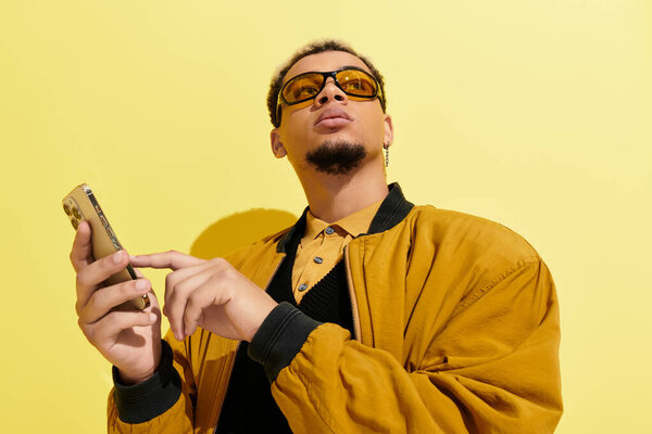 A young african american man showcases his trendy bomber jacket while checking his phone.