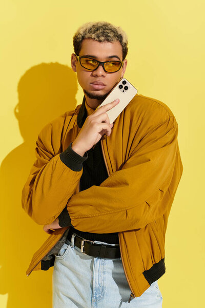 A young african american man stands confidently in a studio, showcasing a fashionable bomber jacket.