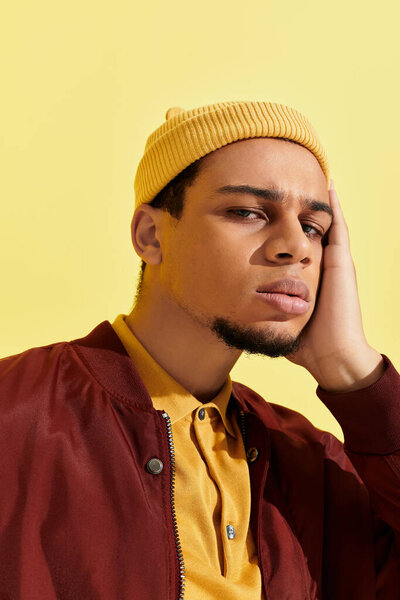 A young african american man poses confidently in a stylish bomber jacket and yellow beanie.