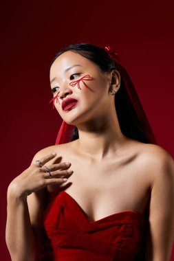 Genç kadın, yanaklarında fiyonklar ve stüdyoda kalın kırmızı dudaklarla yenilikçi bir makyaj sergiliyor..