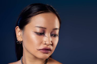 Cesur makyajlı genç bir kadın maviliğe karşı ürkütücü bir hava yaratır..