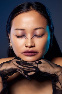 Genç bir Asyalı kadın karmaşık makyajlı ürkütücü bir estetiği kucaklıyor.