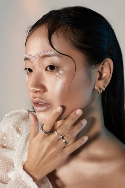 Şık bir stüdyoda inci makyajı yapan Asyalı genç bir kadının eşsiz güzellik ifadesi..