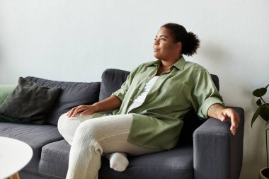 Bir kadın evinde rahat bir şekilde otururken günlük kıyafetlerle huzurlu bir anın tadını çıkarır..