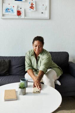 Afro-Amerikalı bir kadın, rahat ve şık bir evle çevrili koltuğunda dinleniyor..