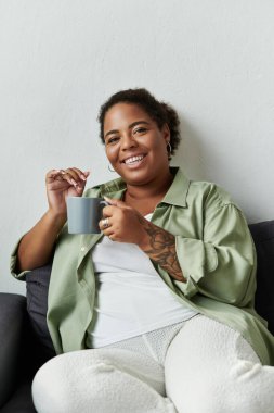 Bir kadın evinde rahat bir anın tadını çıkarır, modern çevrede bir yudum içki içerek..