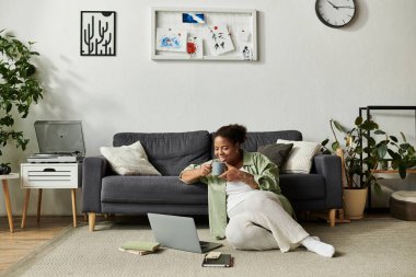 Evde çalışan bir kadın dizüstü bilgisayarıyla yerde dinleniyor, işine odaklanıyor ve işine odaklanıyor..