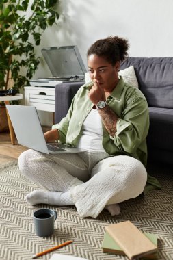 Sıradan giyinmiş siyahi bir kadın, yerde rahat bir şekilde otururken uzaktan kumandalı bir işe girişiyor..