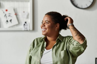 Günlük giysiler içinde neşeli bir kadın saçlarıyla oynar, evinde rahat bir atmosferi kucaklar..