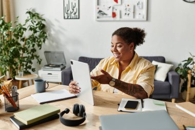 Neşeli bir Afrikalı Amerikalı kadın, evdeki rahat çalışma alanından meslektaşlarıyla etkileşime geçiyor..
