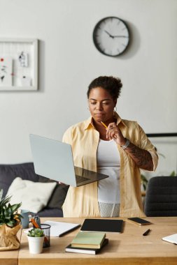 Afrika kökenli Amerikalı bir kadın masasında notları dikkatle incelerken uzaktan kumandayla uğraşıyor..