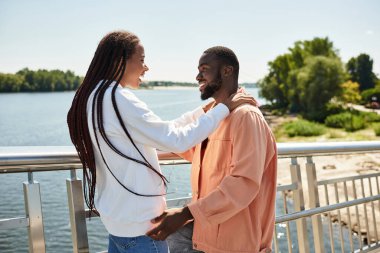 Sevgi dolu bir çift güneşli bir günde nehir kenarında yürürken keyifli bir anı paylaşır..