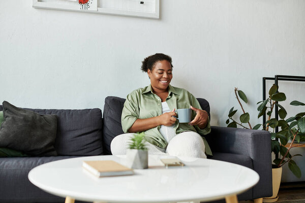 Афроамериканка наслаждается своим временем дома, мирно потягивая чай в своем уютном месте.