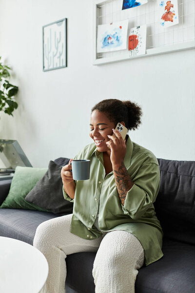 Афроамериканка наслаждается уютным днем в своей стильной квартире, счастливо болтая.