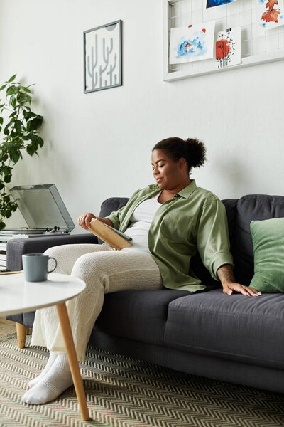 A woman in casual attire lounges on her sofa, enjoying a moment of peace in her stylish apartment.