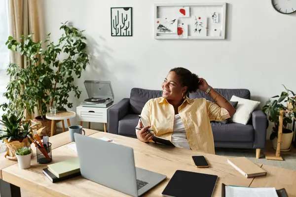 Rahat bir Afrikalı Amerikalı kadın evinde laptopuyla çalışıyor. Etrafı yeşilliklerle çevrili..