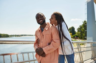 Genç bir çift, sakin bir gölün yanında yürürken birbirlerine eşlik etmekten zevk alır..