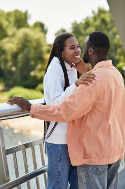 Sevgi dolu bir çift, birlikte tatlı bir anın tadını çıkarır. Nehir kenarında yürürken gülümser ve bağlanır..
