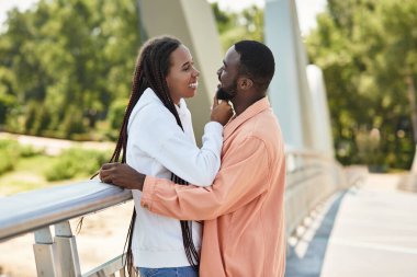 Genç bir çift, güneşli bir günde doğada yürürken kahkaha ve şefkatten zevk alır..