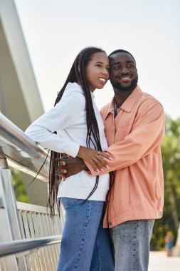 Genç bir çift, güneşli bir günde romantik bir gezinti yapar. Sıcak bir şekilde kucaklaşır ve gülümser..