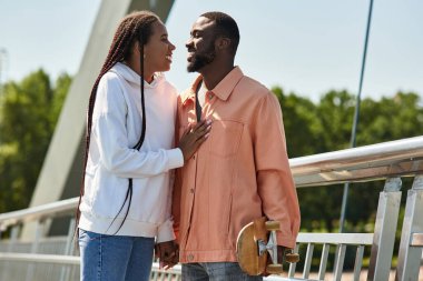 Genç bir çift nehir kenarında el ele yürürken hassas bir anı paylaşıyor..