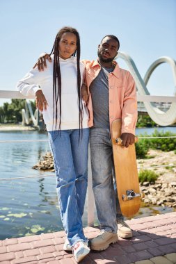 Sıcak güneşin altında birbirini kucaklayan sevgi dolu bir çift nehir kenarında yürüyor..